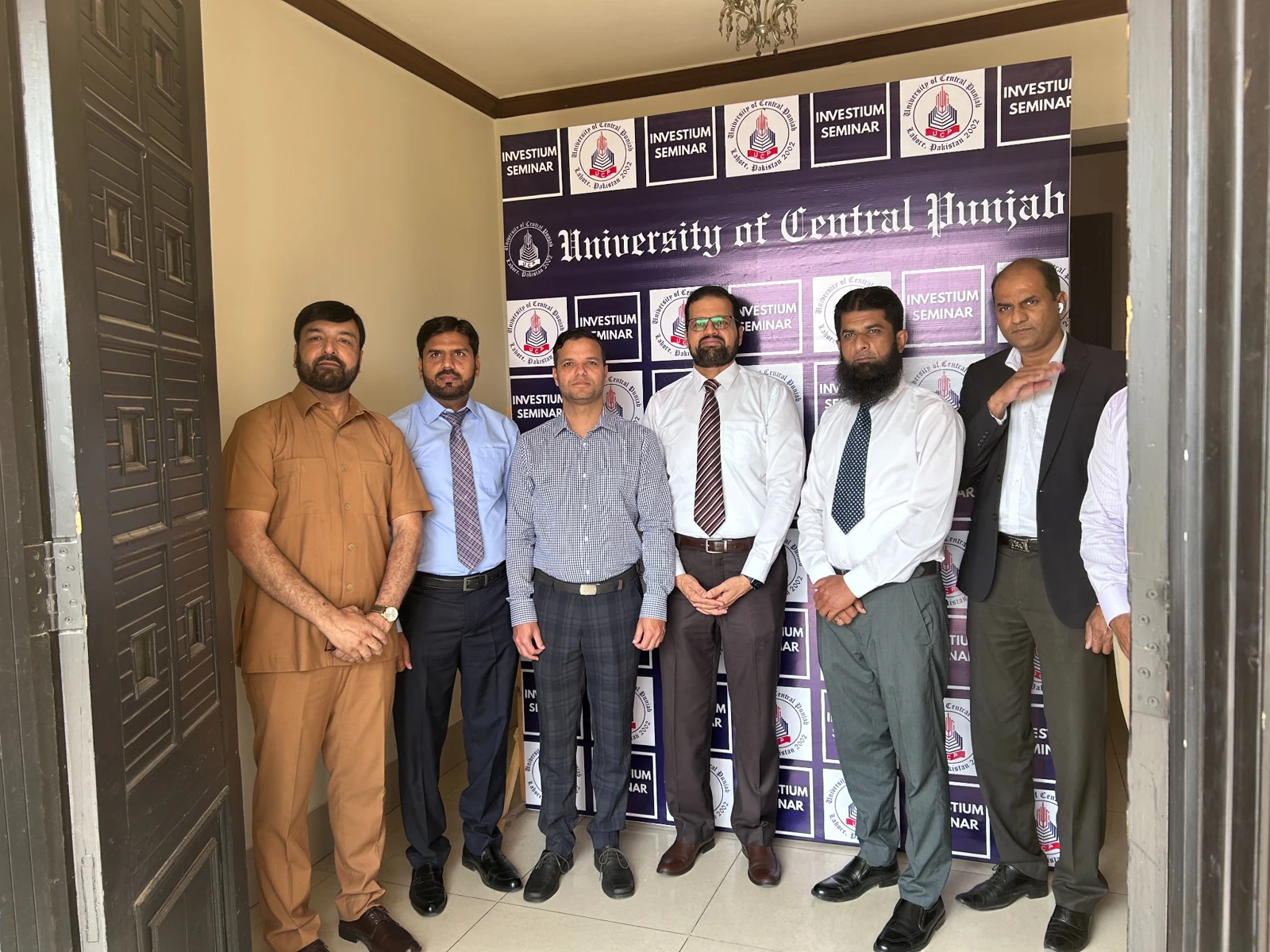 Iftekhar Wasfi with participants in front of the UCP Investium Seminar backdrop